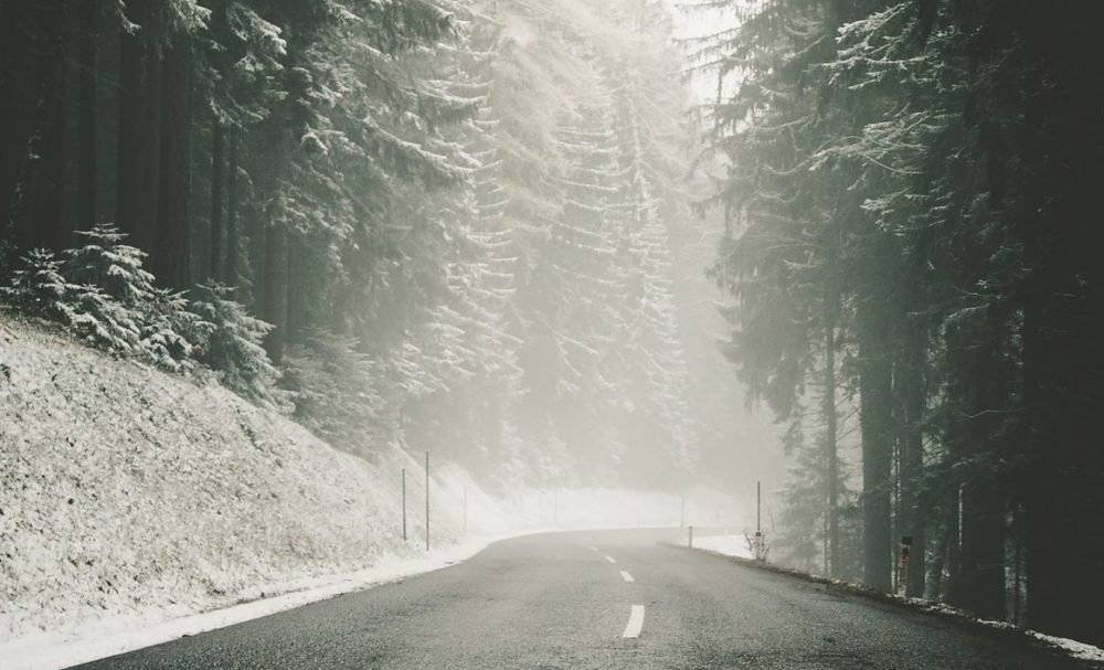 Durch S-Pro EisWeg befreite Straße durch den Wald im Winter.