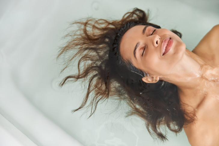 eine Frau hält Ihren Kopf in die Badewanne