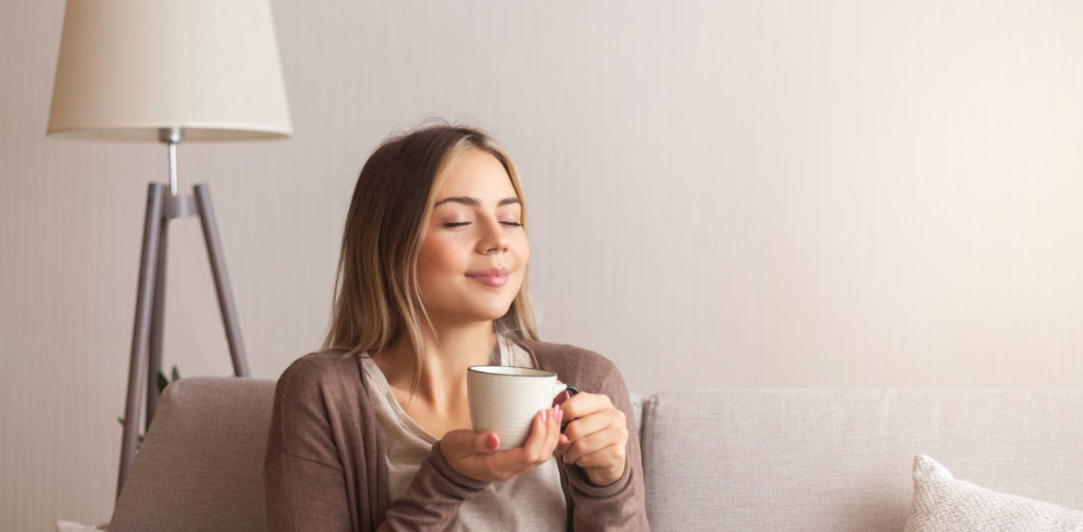 eine Frau mit einem frisch gebrühten Kaffee in der Hand