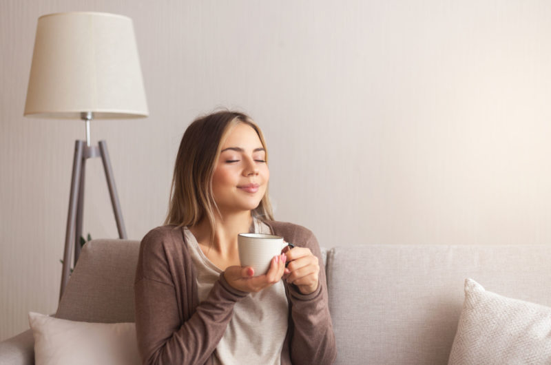 eine Frau mit einem frisch gebrühten Kaffee in der Hand