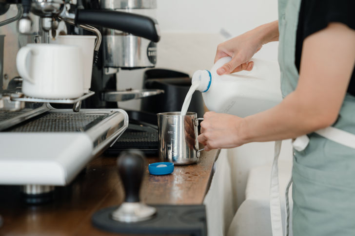 Eine Frau füllt eine Kanne mit Milch