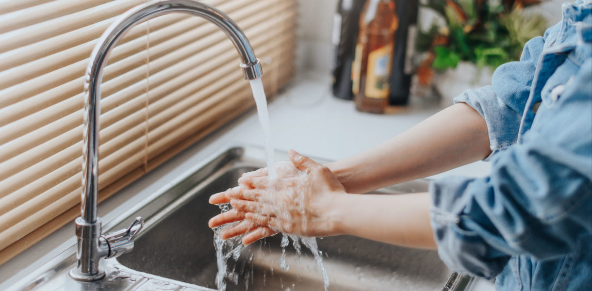 Frau wäscht sich die Hände im Küchenwaschbecken