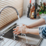Frau wäscht sich die Hände im Küchenwaschbecken