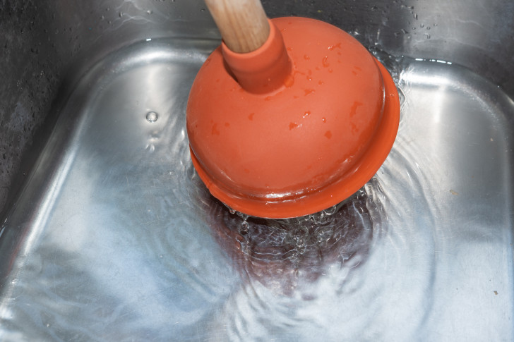 Mit einer Saugglocke wird versucht eine Verstopfung im Küchenabfluss zu lösen
