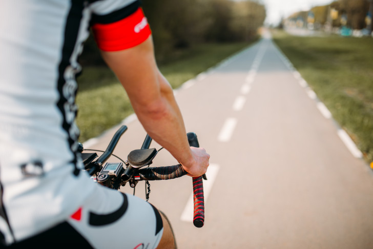 Rennradfahrer in Sportbekleidung fährt eine Straße entlang