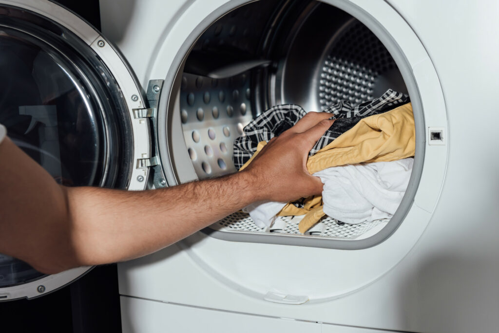 Wäsche wird aus der einer Waschmaschine geholt