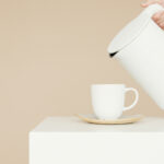 Weiße Tasse wird mit weißem Wasserkocher befüllt