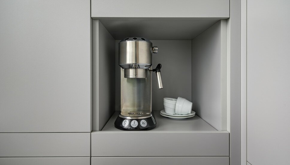 Siebträgerkaffeemaschine in einem grauen Regal.