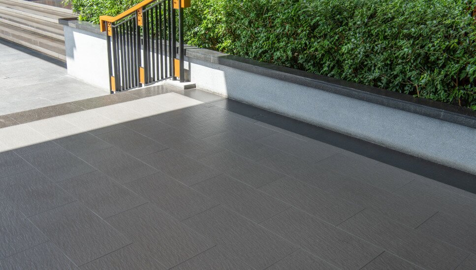 schwarze Terrassenfliesen und ein Holzfarbenes Treppengeländer