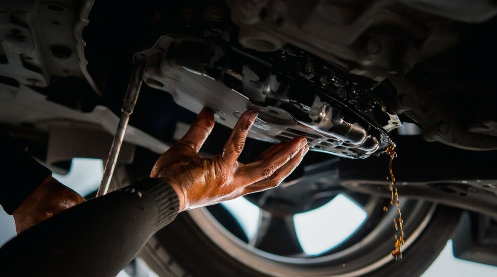 Mechaniker repariert ein Auto das sehr viel Öl verliert.
