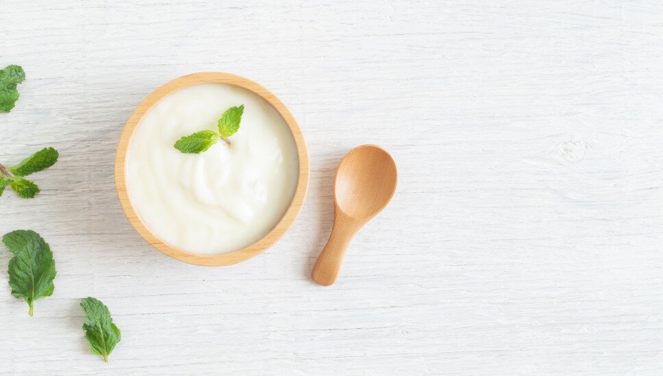 Holzbecher mit Joghurt und Minzblättern.